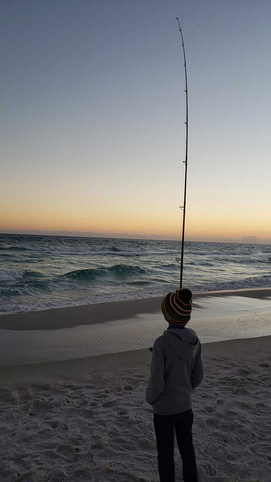 Young Boy Surf Fishing At Dusk On Pensacola Beach